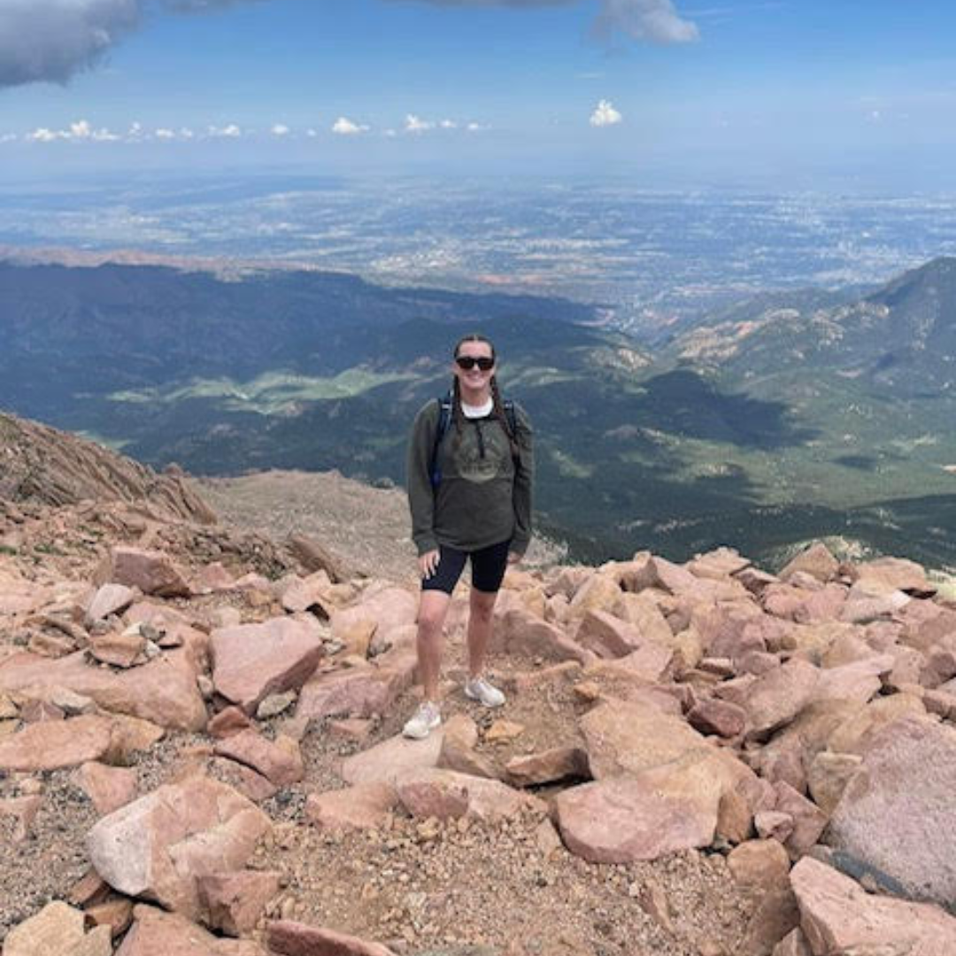 Adult with congenital heart defect posing on top of mountain